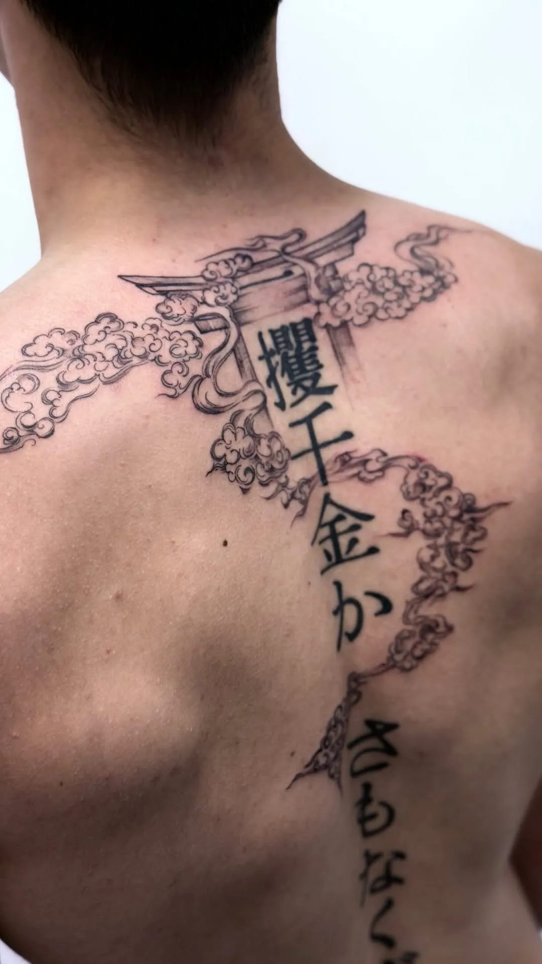 Muguras tetovējums ar japāņu vārtiem, mākoņiem un rakstu zīmēm